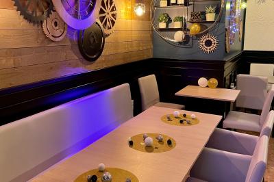 Salle de bar avec tables hautes, chaises, éclairage coloré et jeux de lumière dans une ambiance nocturne.