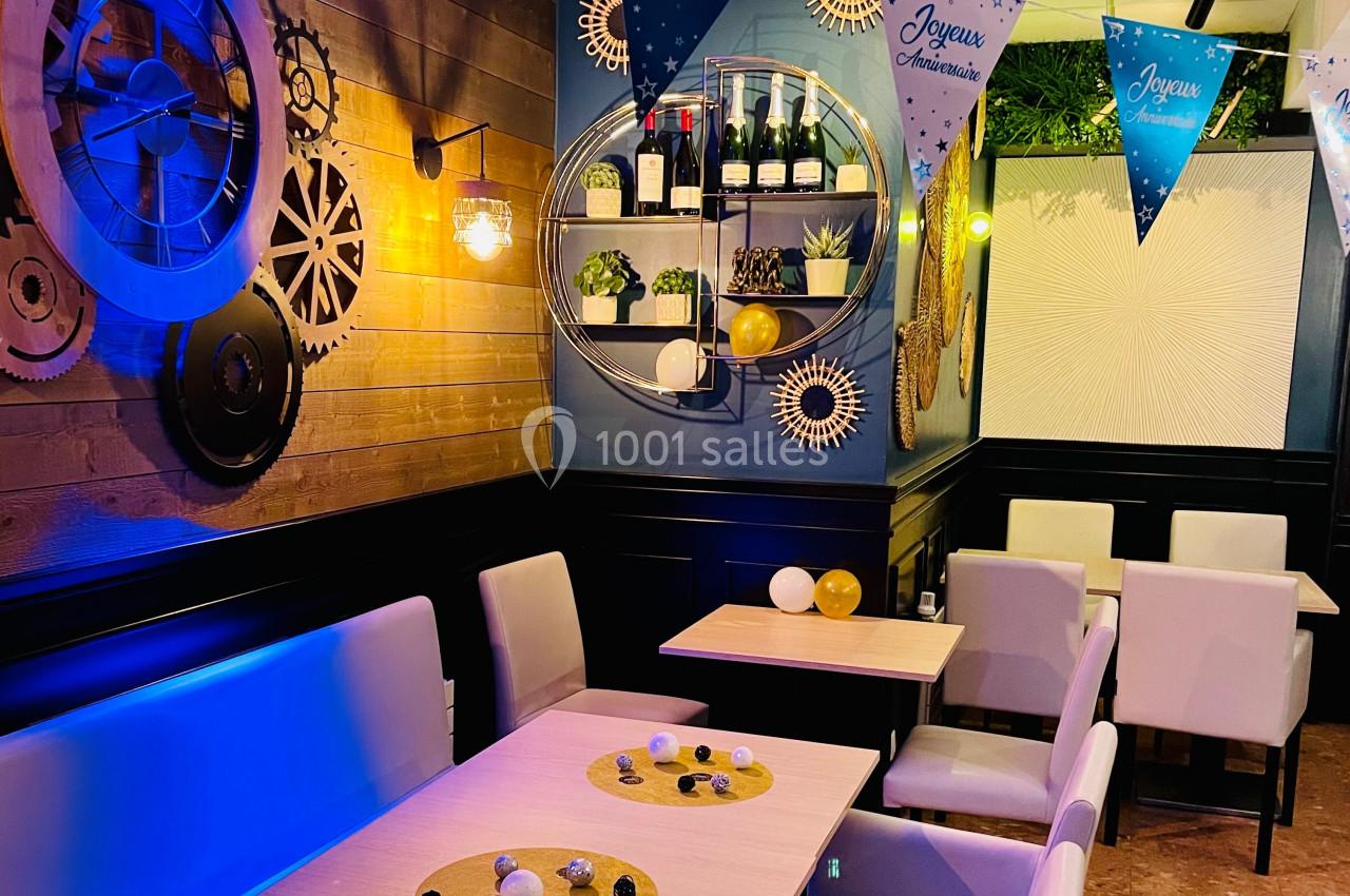 Salle de restaurant décorée pour un anniversaire, avec guirlandes, tables dressées et éclairage chaleureux.