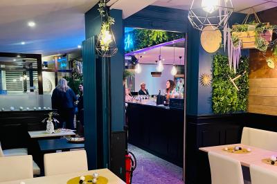 Salle de bar avec tables hautes, chaises, éclairage coloré et jeux de lumière dans une ambiance nocturne.