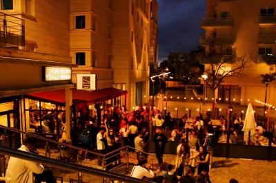 Salle de bar avec tables hautes, chaises, éclairage coloré et jeux de lumière dans une ambiance nocturne.