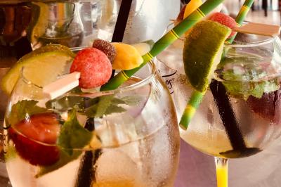 Salle de bar avec tables hautes, chaises, éclairage coloré et jeux de lumière dans une ambiance nocturne.