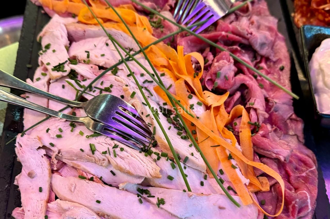 Plateau de tranches de viande blanche et rouge garnies de ciboulette et de lamelles de carotte, avec des fourchettes.