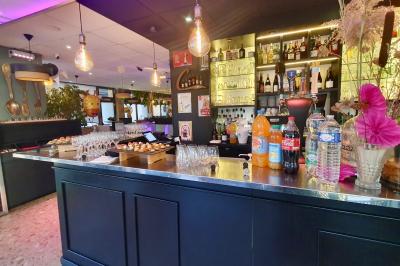 Salle de bar avec tables hautes, chaises, éclairage coloré et jeux de lumière dans une ambiance nocturne.