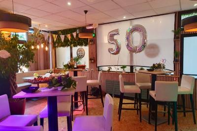 Salle de bar avec tables hautes, chaises, éclairage coloré et jeux de lumière dans une ambiance nocturne.