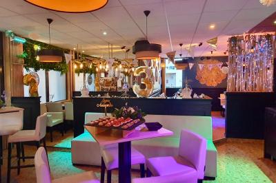 Salle de bar avec tables hautes, chaises, éclairage coloré et jeux de lumière dans une ambiance nocturne.