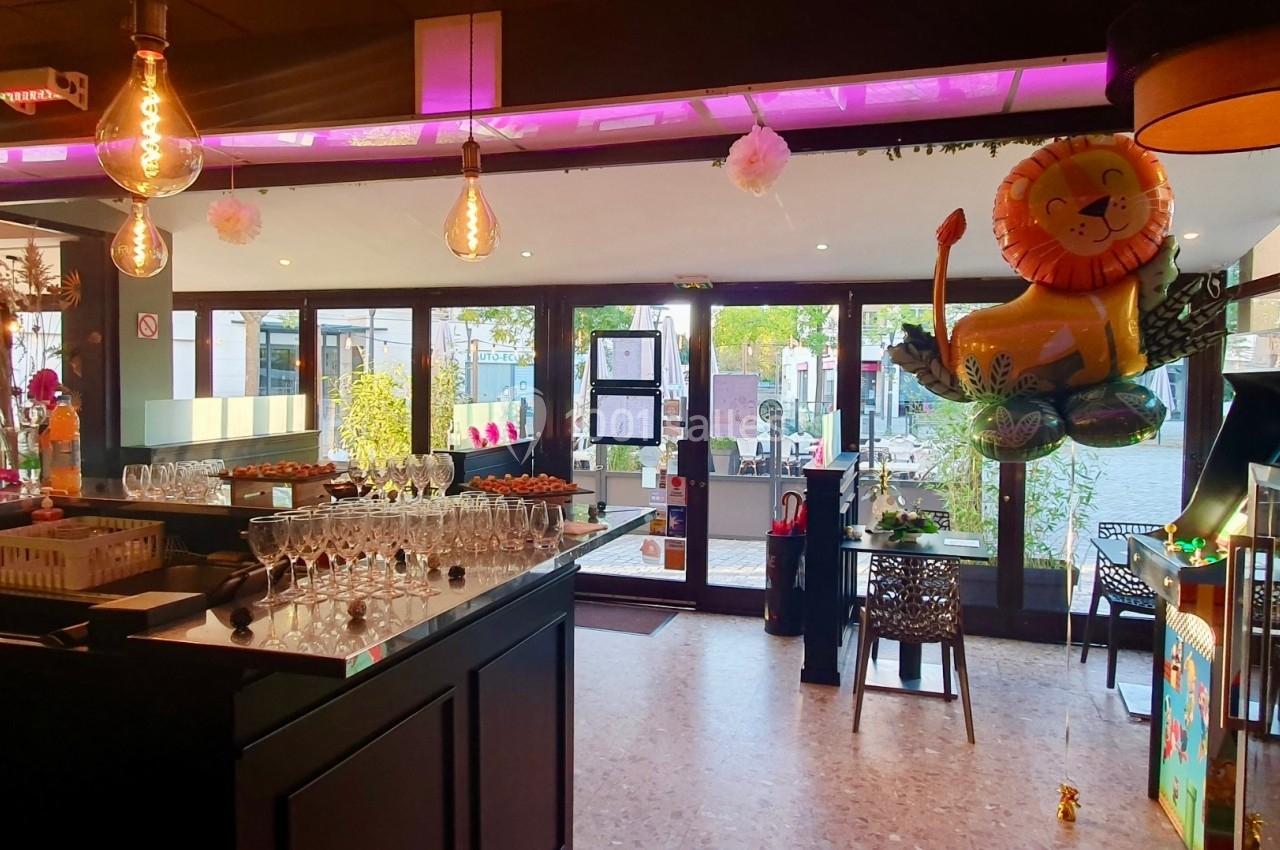 Intérieur d'un café lumineux avec un bar, des tables, des verres alignés et une décoration comprenant un ballon lion.
