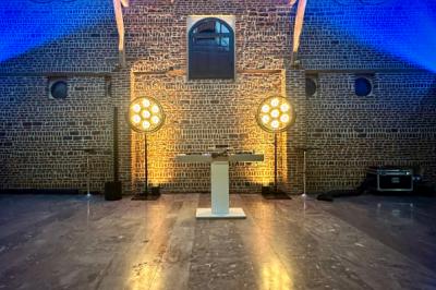 Des invités dansent sous un éclairage coloré dans une salle décorée avec des ballons suspendus et un plafond drapé.