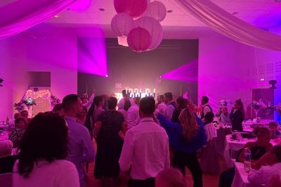 Des invités dansent sous un éclairage coloré dans une salle décorée avec des ballons suspendus et un plafond drapé.