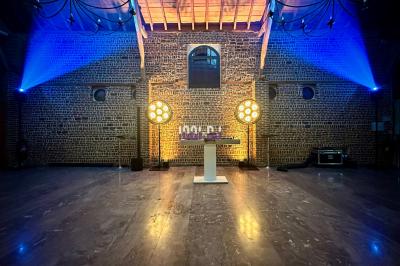 Des invités dansent sous un éclairage coloré dans une salle décorée avec des ballons suspendus et un plafond drapé.