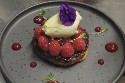 Verrine de dessert composée de crème fouettée, morceaux de pêche et coulis de mangue sur un lit de biscuit.