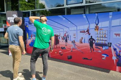 Personnes rassemblées dans une salle élégante, certaines interagissant avec un mur lumineux coloré.