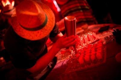 Un cuisinier prépare des desserts en utilisant un siphon, dans une ambiance lumineuse rouge et festive.