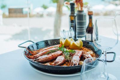 Crevettes grillées servies dans une assiette bleue avec des herbes, accompagnées de plats et d'un verre de vin rouge.