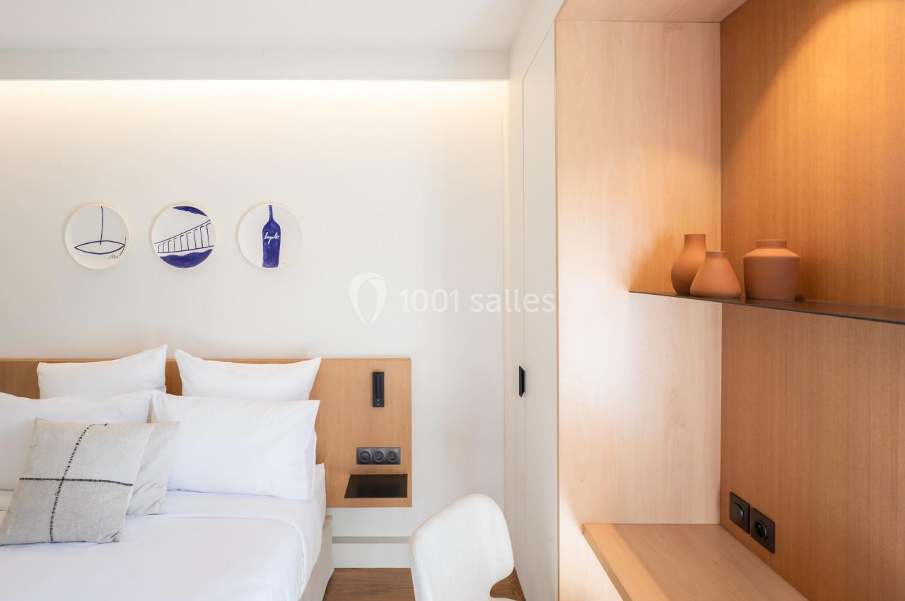 Chambre lumineuse avec lit double, décor minimaliste, étagères en bois et trois décorations murales rondes.