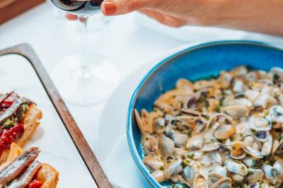 Crevettes grillées servies dans une assiette bleue avec des herbes, accompagnées de plats et d'un verre de vin rouge.