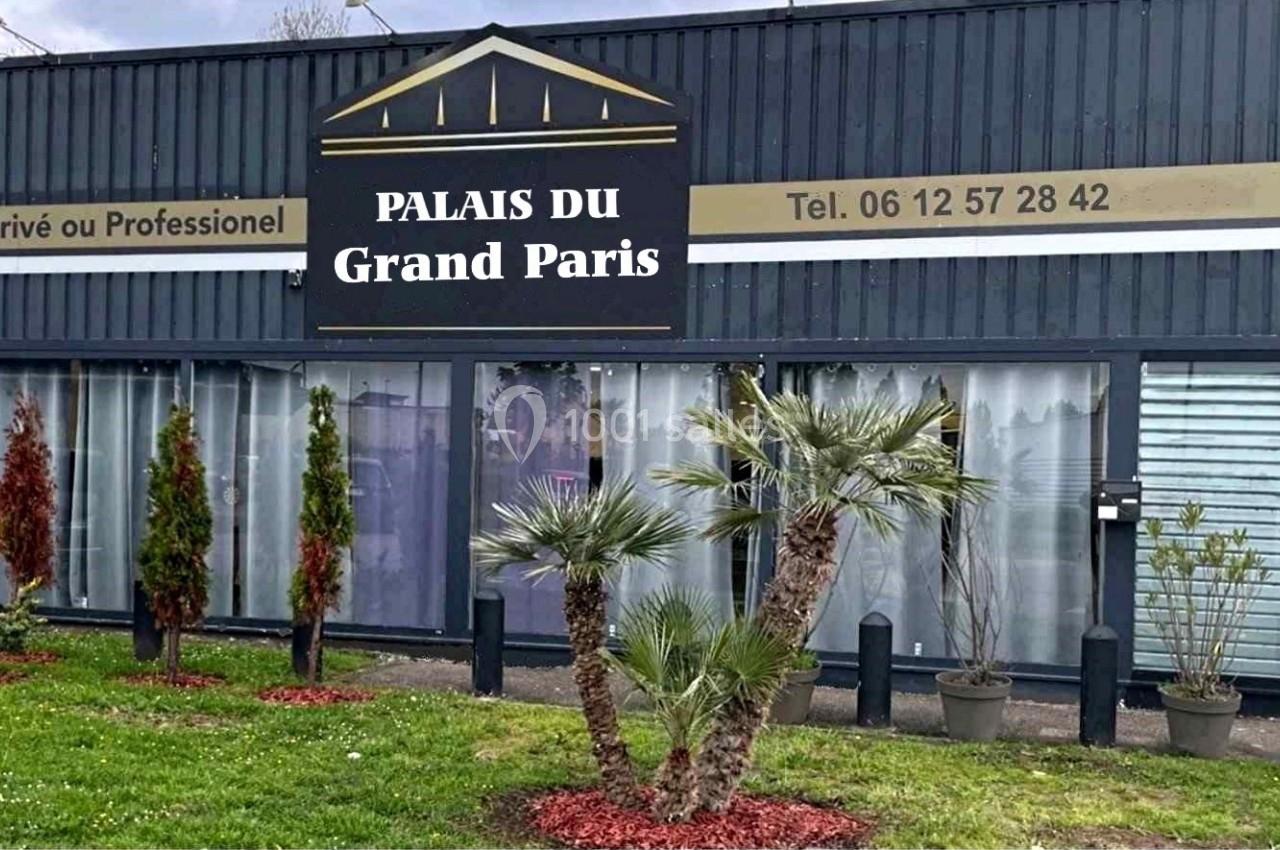 Façade d'un bâtiment avec enseigne ’Palais du Grand Paris’, entourée de plantes et d'une pelouse entretenue.