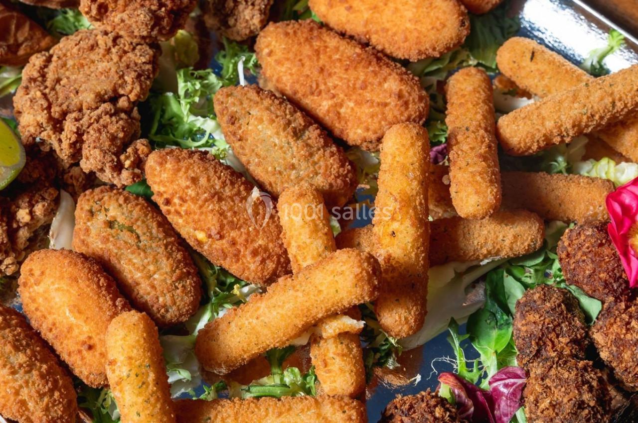 Assortiment de snacks panés variés disposés sur un lit de salade verte.