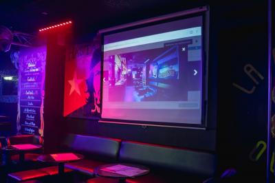 Écran de projection affichant une image d'intérieur coloré dans un espace sombre avec sièges et éclairage néon.