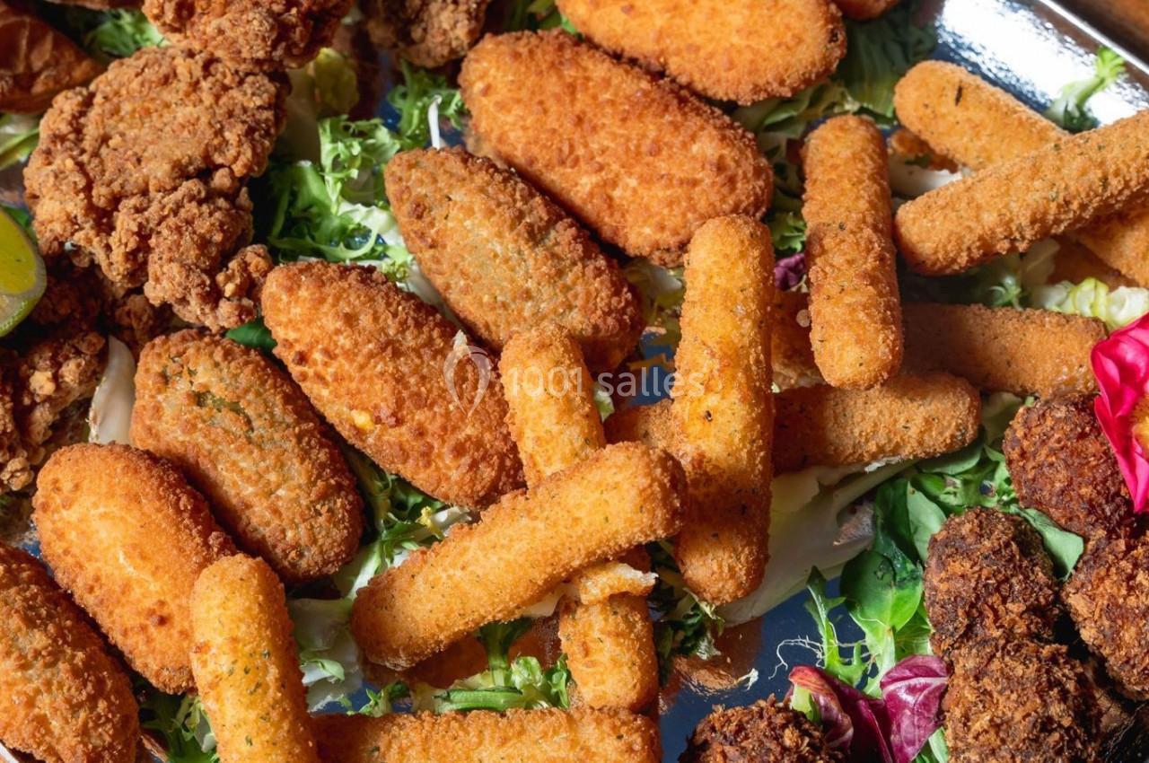 Assortiment de snacks frits, dont bâtonnets de mozzarella, nuggets et falafels, disposés sur un lit de salade.