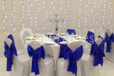 Miniature Location salle Bagnolet (Seine-Saint-Denis) - La Girafe #7 Salle décorée pour un événement avec tables rondes, nappes blanches, chaises ornées de nœuds argentés et dorés, éclairage…