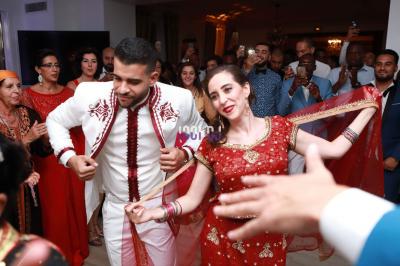 Des mariés avancent sous des étincelles tenues par des invités, entourés d'une foule prenant des photos.