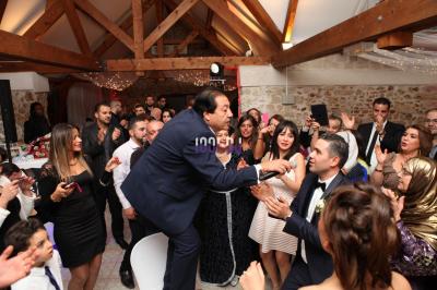 Des mariés avancent sous des étincelles tenues par des invités, entourés d'une foule prenant des photos.