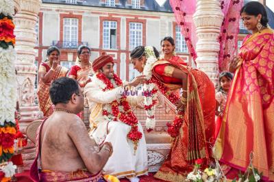 Des mariés avancent sous des étincelles tenues par des invités, entourés d'une foule prenant des photos.