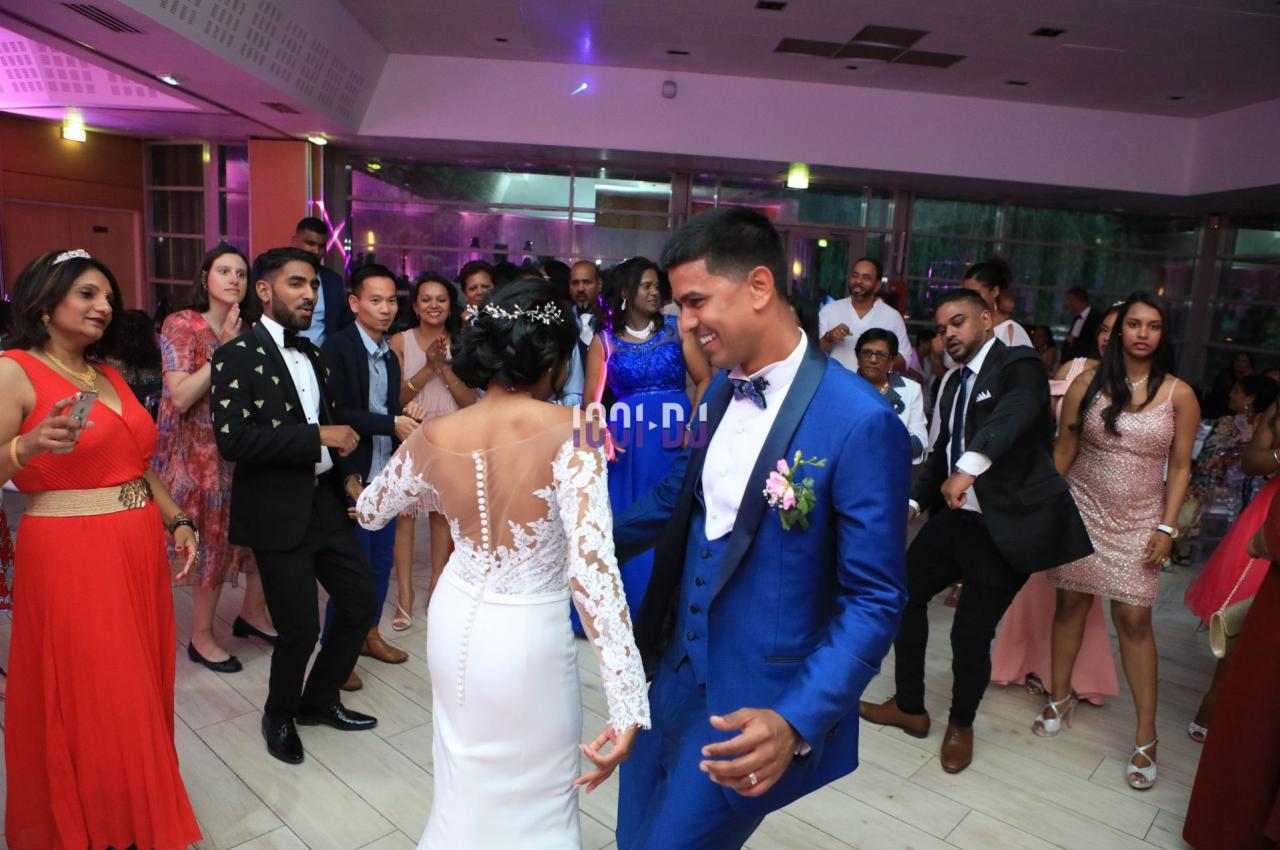 Un couple danse au centre d'une salle de réception entouré d'invités en tenue de soirée.