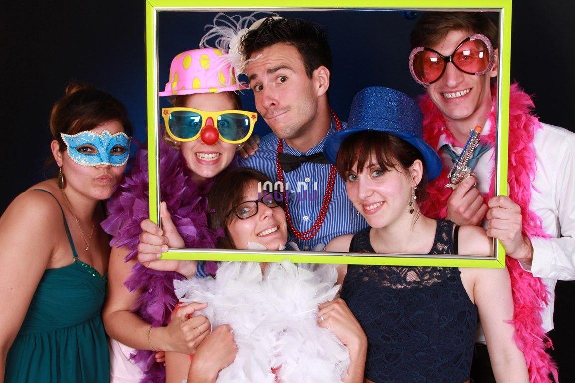 Des personnes déguisées avec des accessoires festifs posent ensemble derrière un cadre coloré.