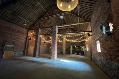 Parking en gravier entouré d'arbres et de bâtiments en briques sous un ciel partiellement nuageux.