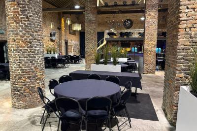 Parking en gravier entouré d'arbres et de bâtiments en briques sous un ciel partiellement nuageux.