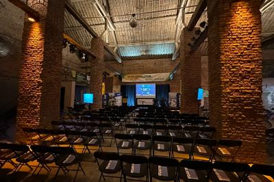Parking en gravier entouré d'arbres et de bâtiments en briques sous un ciel partiellement nuageux.