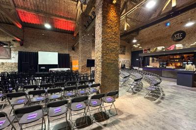 Parking en gravier entouré d'arbres et de bâtiments en briques sous un ciel partiellement nuageux.