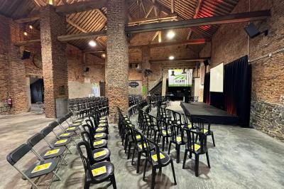 Parking en gravier entouré d'arbres et de bâtiments en briques sous un ciel partiellement nuageux.