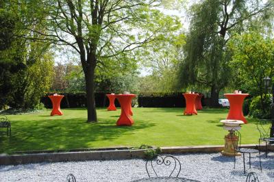 Parking en gravier entouré d'arbres et de bâtiments en briques sous un ciel partiellement nuageux.
