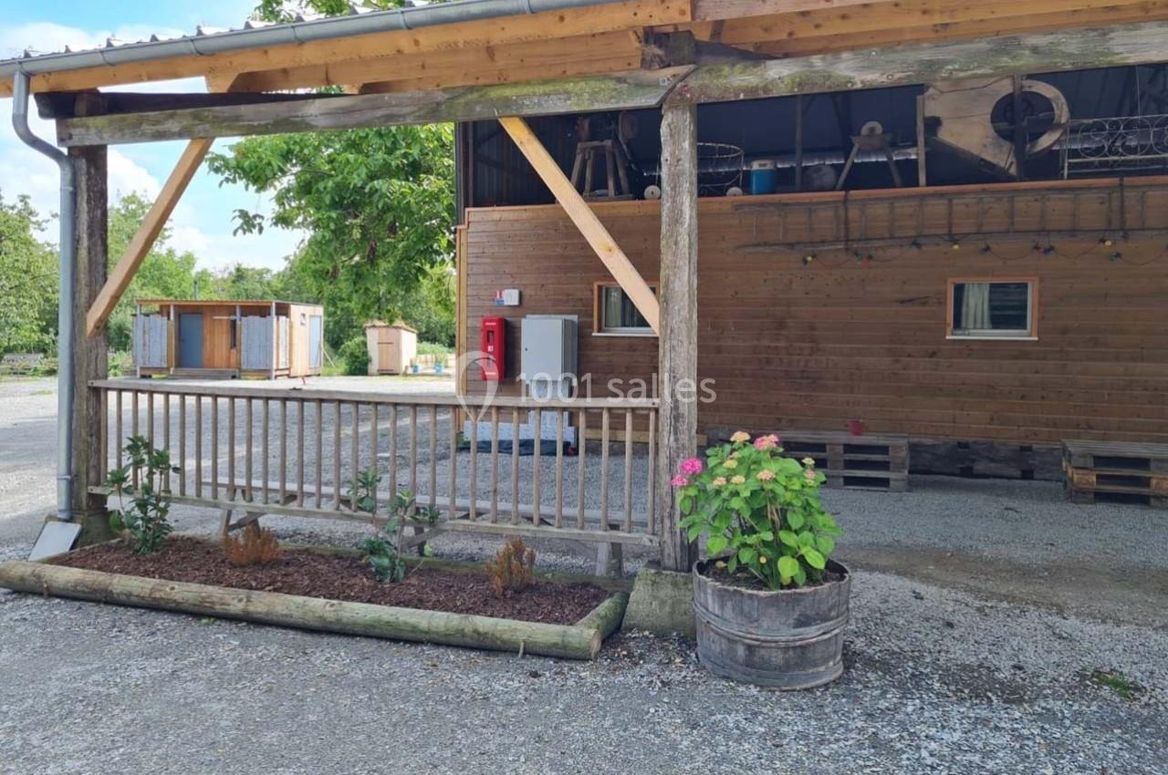 Abri en bois avec jardinière, plantes et équipements visibles, situé dans un espace extérieur gravillonné.