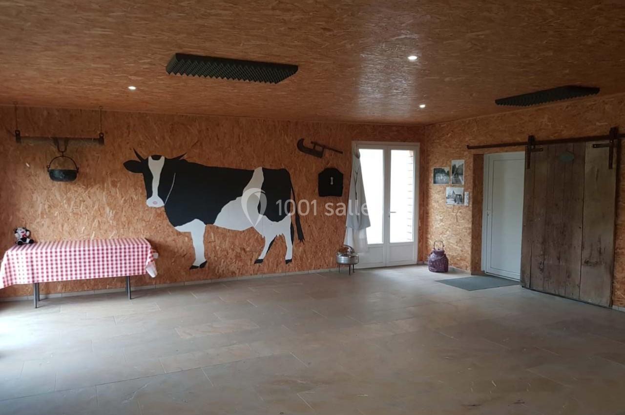 Salle avec murs en bois, une fresque de vache, table à nappe rouge et blanche, et portes coulissantes en bois.