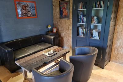 Coin salon avec canapé, fauteuils en cuir, table basse avec jeu d'échecs, bibliothèque et décorations murales.