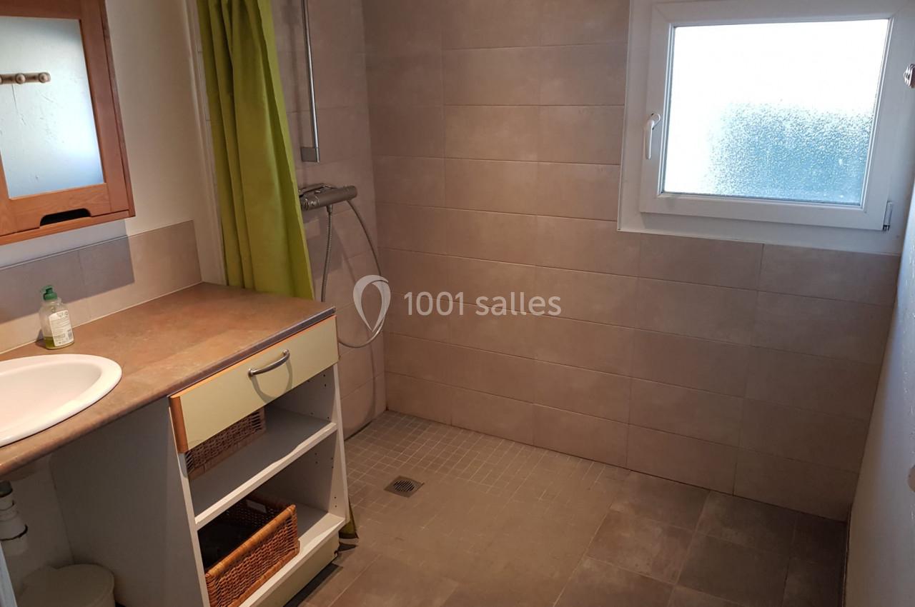 Salle de bain avec douche à l'italienne, fenêtre opaque, meuble sous lavabo et rideau de douche vert.