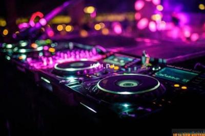 Table de mixage éclairée par des lumières colorées dans une ambiance de soirée ou de concert.