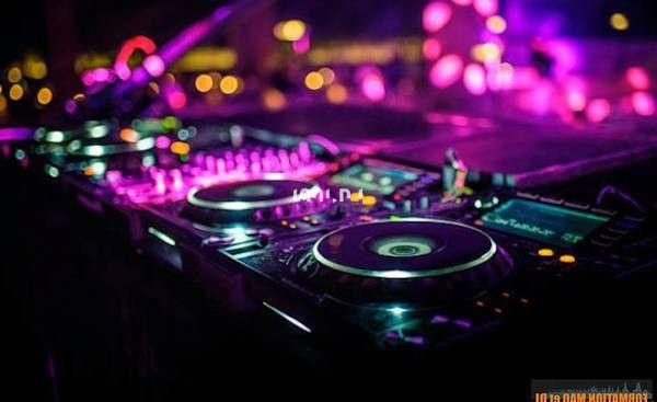 Table de mixage éclairée par des lumières colorées dans une ambiance de soirée ou de concert.