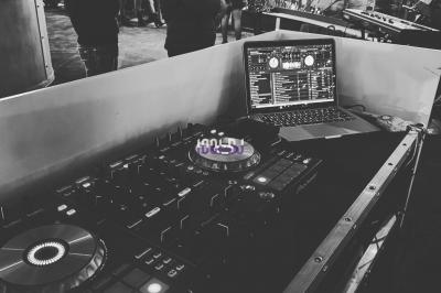 Miniature DJ Moisenay (Seine-et-Marne) - DJ Joss #3 Un DJ souriant se tient devant son équipement lumineux dans une salle décorée pour un événement.