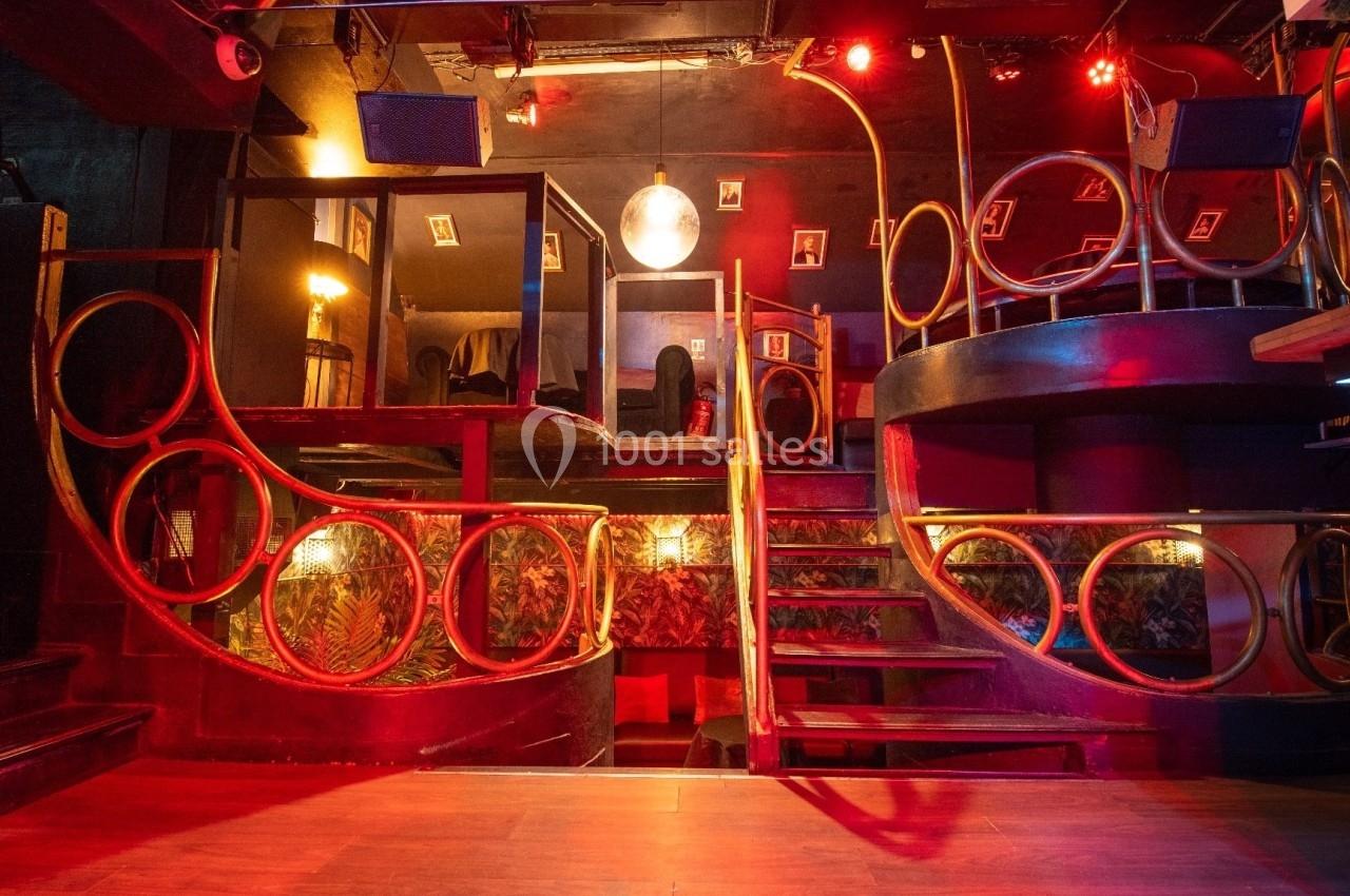 Intérieur d'un bar avec des structures en bois arrondies, éclairage rouge et ambiance tamisée.