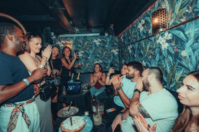 Deux femmes souriantes posent ensemble dans un environnement festif avec un éclairage tamisé.
