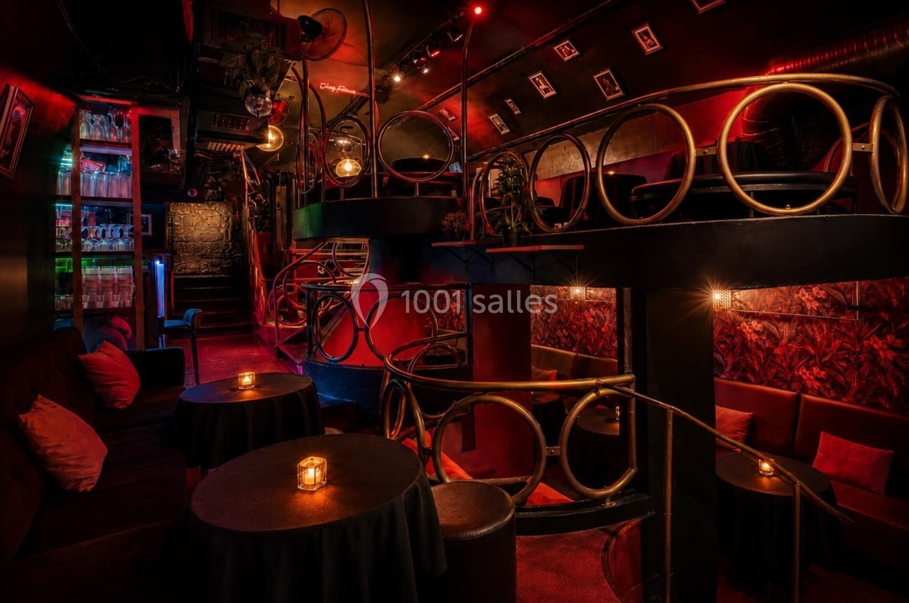 Intérieur d'un bar lounge avec éclairage tamisé, tables rondes, bougies et décorations en métal doré.