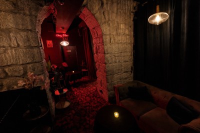 Entrée sombre d'un bâtiment avec un néon en forme de couronne, encadrée par deux grands pots de fleurs.