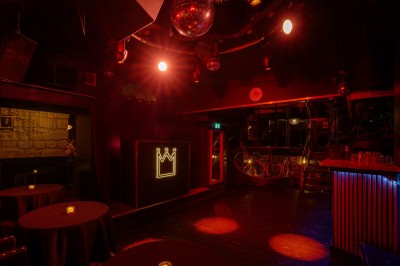 Miniature Location salle Paris 6 (Paris) - Chez Prince #4 Entrée d'un bar ou club avec une enseigne lumineuse en forme de couronne, vélo stationné à gauche et cordon de sécurité.