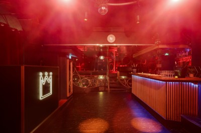 Miniature Location salle Paris 6 (Paris) - Chez Prince #27 Entrée d'un bar ou club avec une enseigne lumineuse en forme de couronne, vélo stationné à gauche et cordon de sécurité.