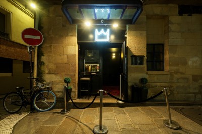 Miniature Location salle Paris 6 (Paris) - Chez Prince #30 Entrée d'un bar ou club avec une enseigne lumineuse en forme de couronne, vélo stationné à gauche et cordon de sécurité.