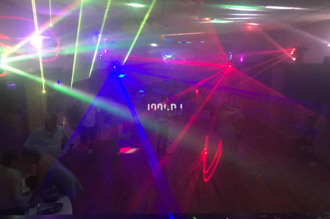 Salle sombre avec des jeux de lumières colorées et des personnes dansant sur une piste.